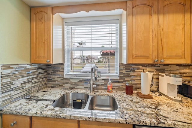 kitchen featuring light stone countertops, decorative backsplash, and sink