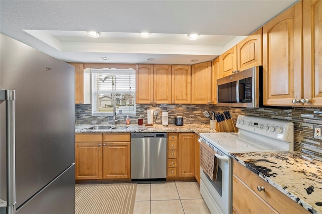 kitchen featuring light stone counters, light tile patterned floors, decorative backsplash, appliances with stainless steel finishes, and sink