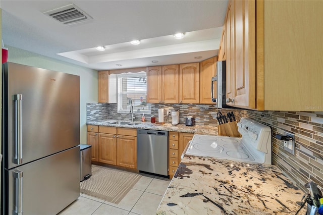 kitchen with sink, light stone counters, light tile patterned floors, backsplash, and appliances with stainless steel finishes