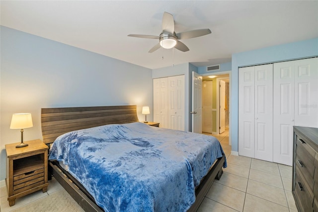 tiled bedroom featuring two closets and ceiling fan