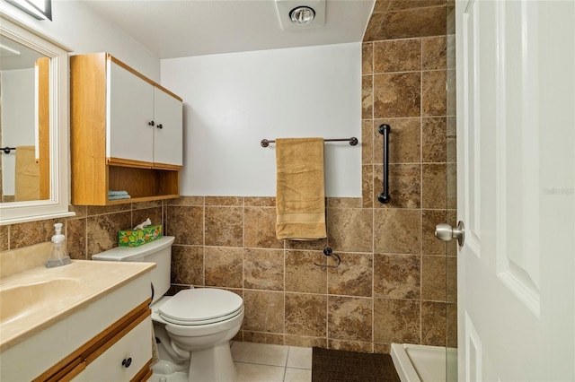 bathroom with toilet, a shower, tile patterned flooring, tile walls, and vanity