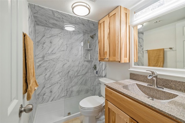 bathroom featuring toilet, a tile shower, and vanity