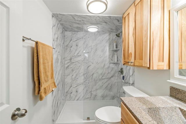 bathroom featuring toilet, a tile shower, and vanity