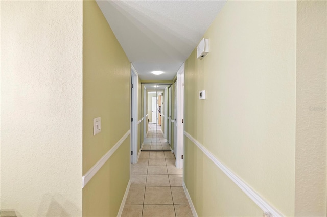 hall featuring a textured ceiling and light tile patterned floors