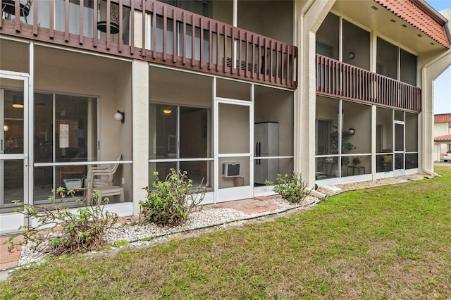 back of property featuring a sunroom and a lawn