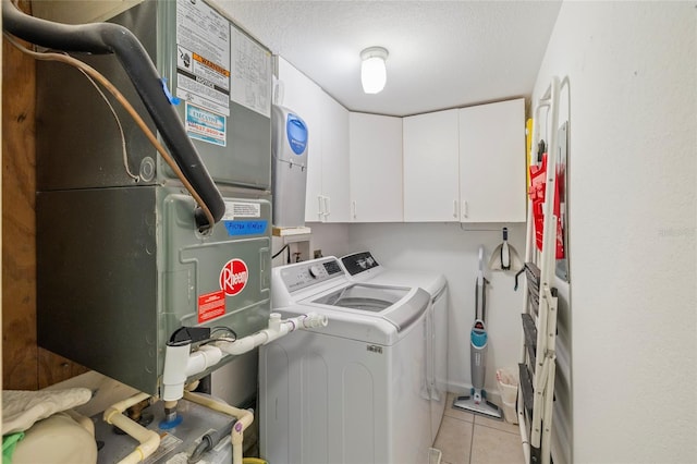 washroom with a textured ceiling, light tile patterned floors, cabinets, heating unit, and separate washer and dryer