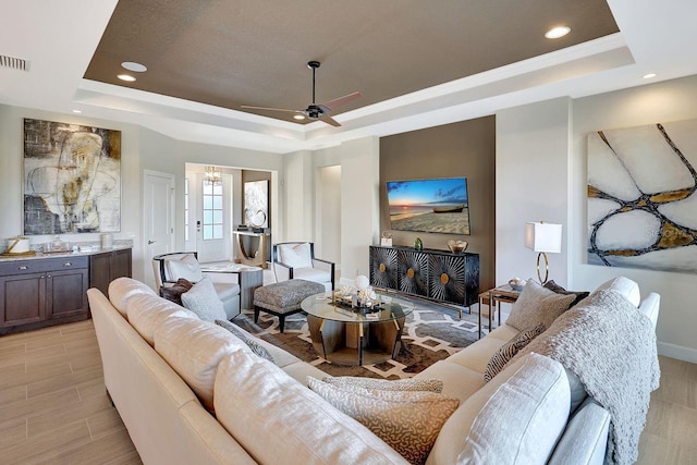 living room with crown molding, ceiling fan, and a tray ceiling