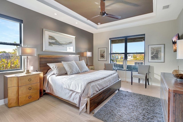 bedroom featuring multiple windows, a raised ceiling, and ceiling fan