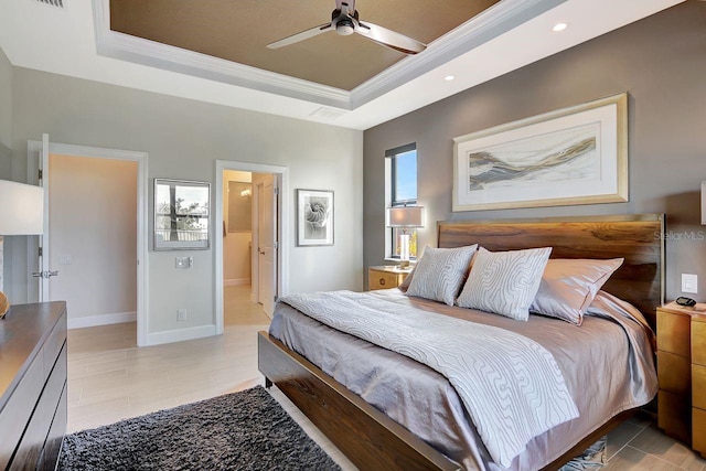 bedroom with a raised ceiling, crown molding, connected bathroom, and ceiling fan