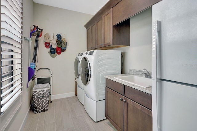 washroom featuring washer and dryer, plenty of natural light, sink, and cabinets