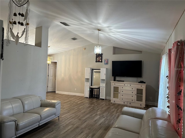 living room featuring dark wood-type flooring, vaulted ceiling, and a chandelier