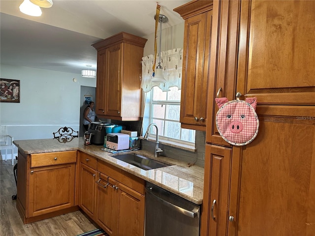 kitchen featuring dishwasher, kitchen peninsula, pendant lighting, sink, and light hardwood / wood-style flooring