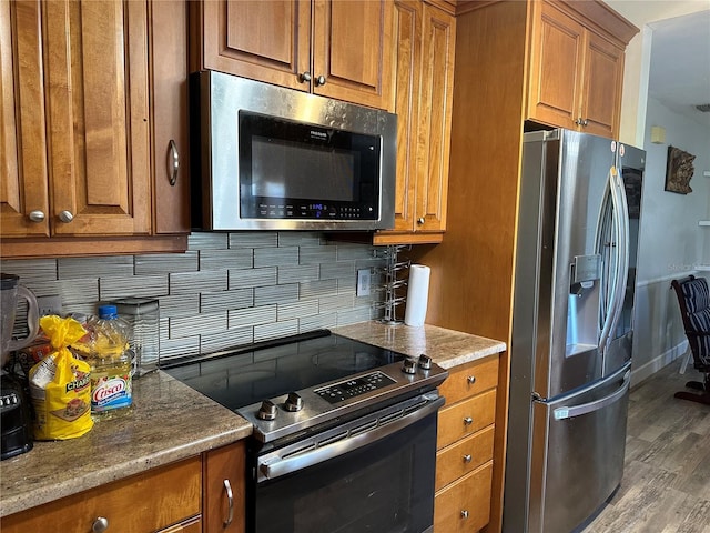 kitchen featuring light stone countertops, stainless steel appliances, dark hardwood / wood-style floors, and decorative backsplash