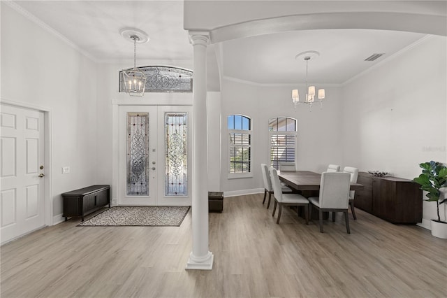 foyer featuring french doors, ornate columns, ornamental molding, a notable chandelier, and light hardwood / wood-style floors