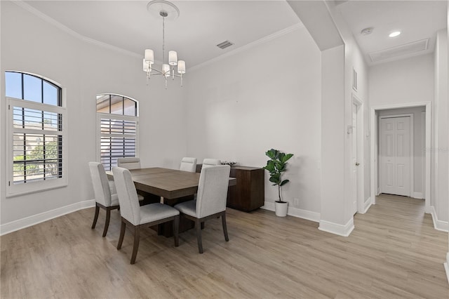 dining area featuring a chandelier, a towering ceiling, light wood-type flooring, and crown molding