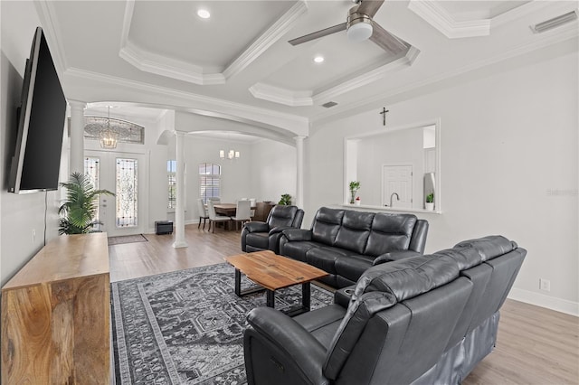 living room featuring ceiling fan with notable chandelier, light wood-type flooring, crown molding, and coffered ceiling