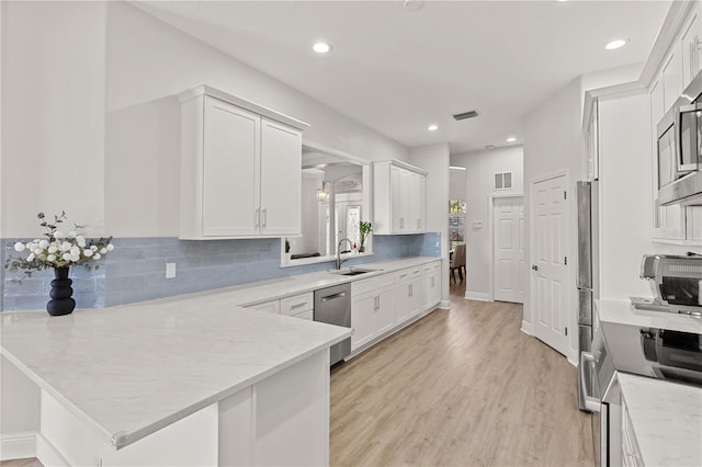 kitchen featuring white cabinets, sink, light hardwood / wood-style flooring, decorative backsplash, and kitchen peninsula