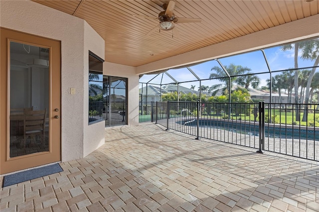 view of patio with a fenced in pool, glass enclosure, and ceiling fan