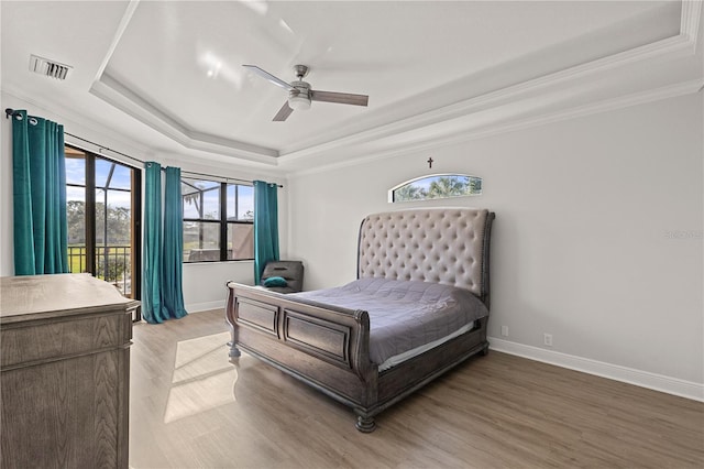 bedroom featuring hardwood / wood-style floors, ceiling fan, a raised ceiling, and ornamental molding