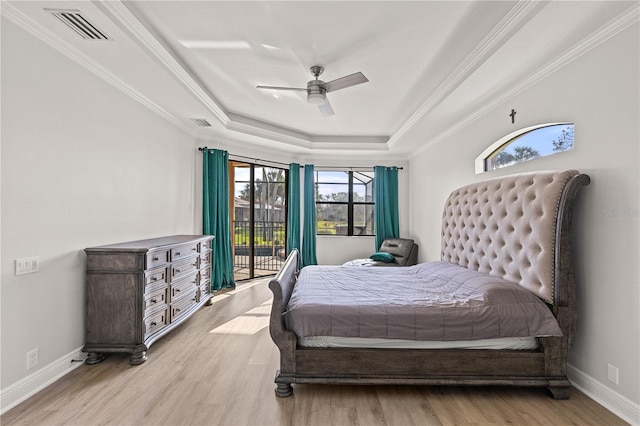 bedroom featuring access to exterior, a raised ceiling, ceiling fan, crown molding, and light hardwood / wood-style floors