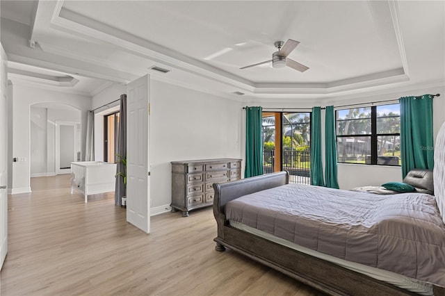 bedroom featuring ceiling fan, a raised ceiling, light wood-type flooring, and crown molding