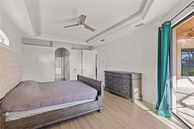 bedroom with a tray ceiling, multiple windows, ceiling fan, and light hardwood / wood-style flooring