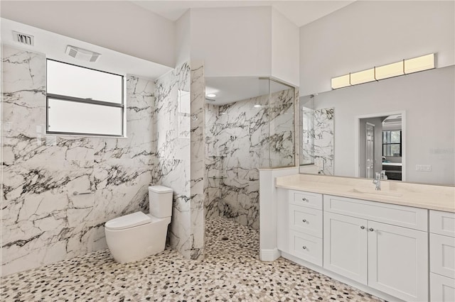 bathroom with a tile shower, vanity, toilet, and plenty of natural light