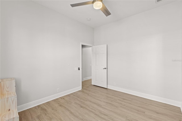 unfurnished room with ceiling fan, a towering ceiling, and light hardwood / wood-style flooring