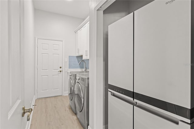 washroom with washer and clothes dryer, cabinets, sink, and light hardwood / wood-style flooring