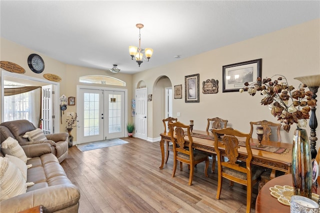 dining space with light hardwood / wood-style floors, an inviting chandelier, and french doors