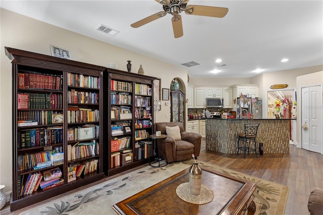 living area with wood-type flooring and ceiling fan