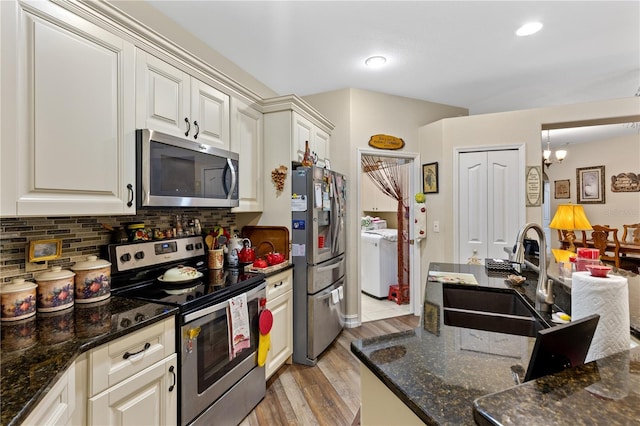 kitchen with sink, tasteful backsplash, independent washer and dryer, a chandelier, and appliances with stainless steel finishes