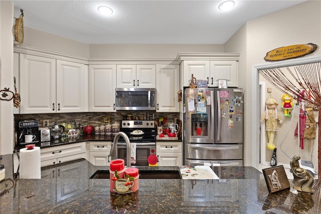 kitchen with backsplash, white cabinets, dark stone countertops, appliances with stainless steel finishes, and kitchen peninsula