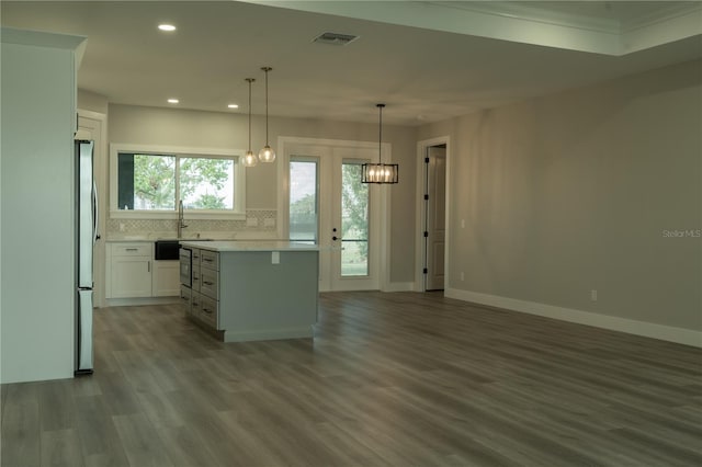 kitchen with pendant lighting, stainless steel fridge, white cabinetry, tasteful backsplash, and a kitchen island