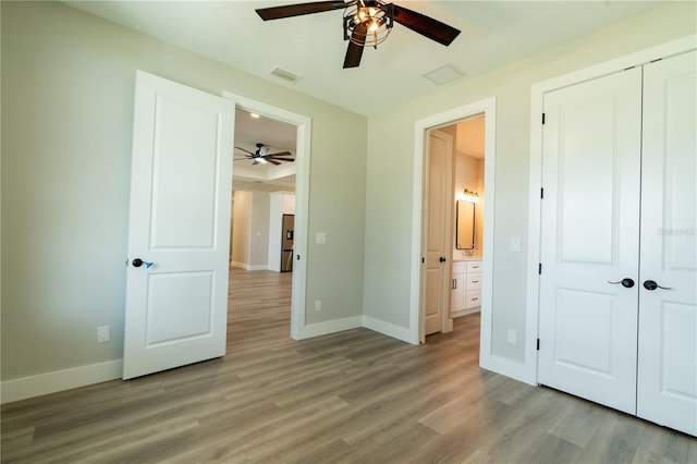 unfurnished bedroom with light hardwood / wood-style flooring, a closet, ceiling fan, and stainless steel refrigerator with ice dispenser