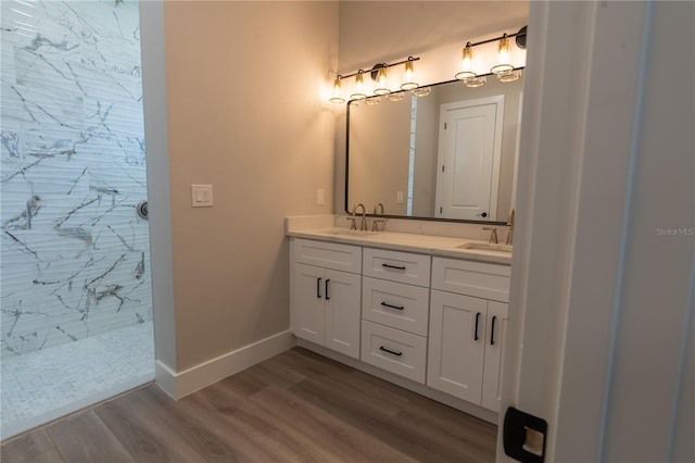 bathroom with hardwood / wood-style flooring, tiled shower, and vanity