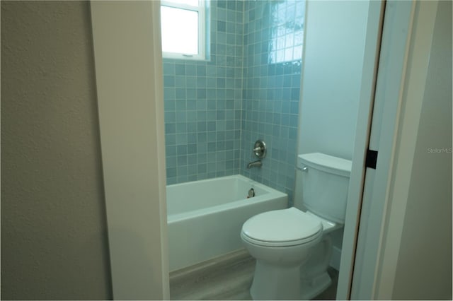 bathroom with tiled shower / bath, hardwood / wood-style floors, and toilet