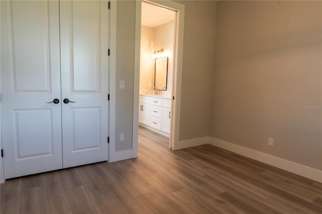 unfurnished bedroom featuring wood-type flooring, sink, and a closet