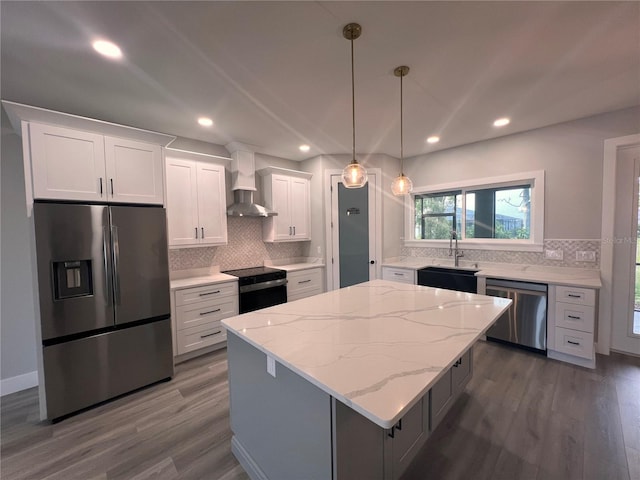 kitchen with wall chimney exhaust hood, sink, white cabinetry, a center island, and stainless steel appliances