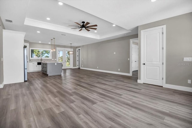 unfurnished living room with a raised ceiling, visible vents, and baseboards