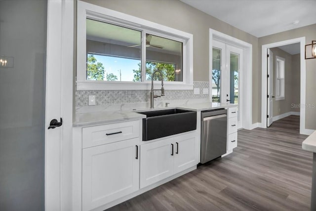 kitchen with light stone counters, white cabinetry, a sink, wood finished floors, and dishwasher