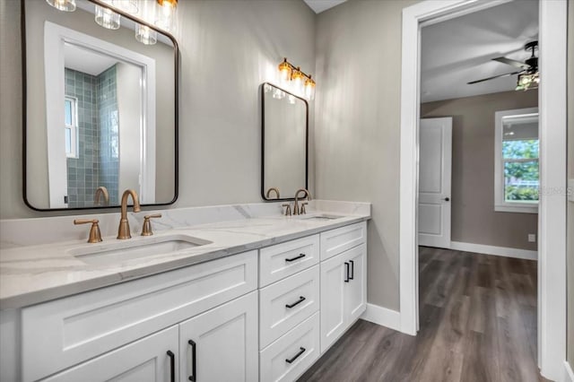 bathroom featuring double vanity, a sink, baseboards, and wood finished floors