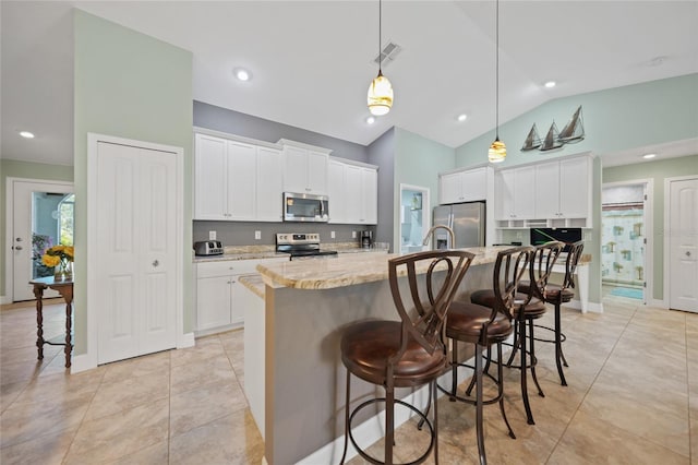 kitchen with stainless steel appliances, vaulted ceiling, a center island with sink, and a kitchen breakfast bar