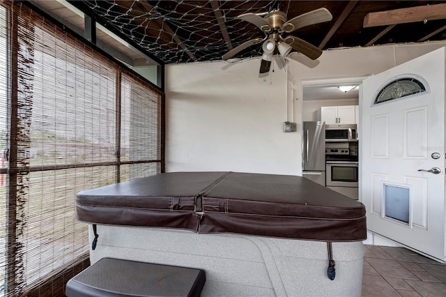 interior space featuring ceiling fan, stainless steel appliances, and white cabinetry