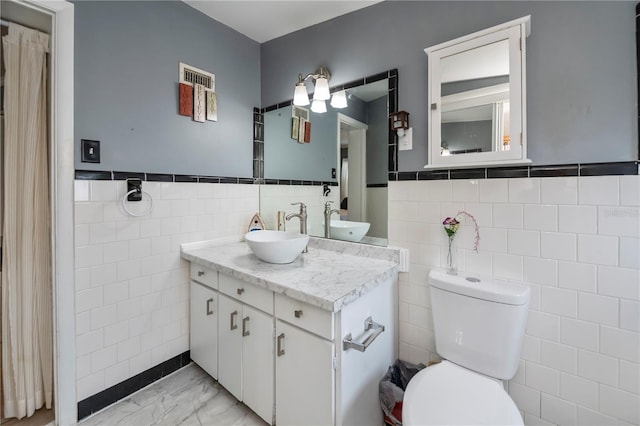 bathroom featuring toilet, vanity, and tile walls