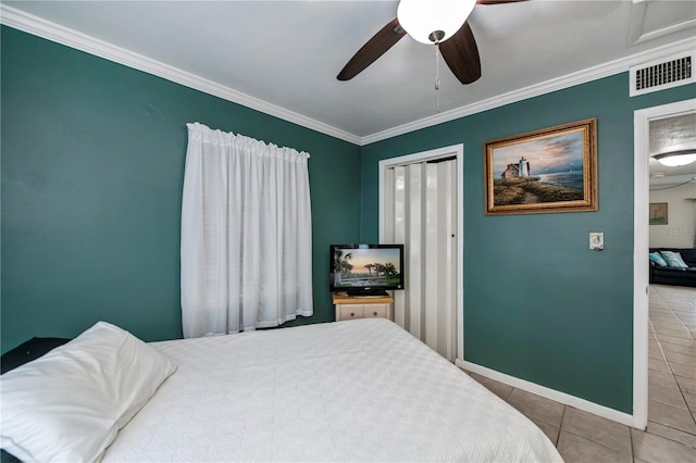 tiled bedroom with ceiling fan, crown molding, and a closet