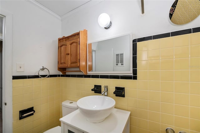 bathroom with toilet, ornamental molding, tile walls, and vanity