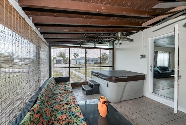 unfurnished sunroom with ceiling fan, plenty of natural light, lofted ceiling with beams, and wooden ceiling