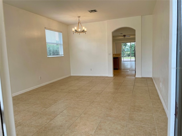 tiled spare room with plenty of natural light and a chandelier