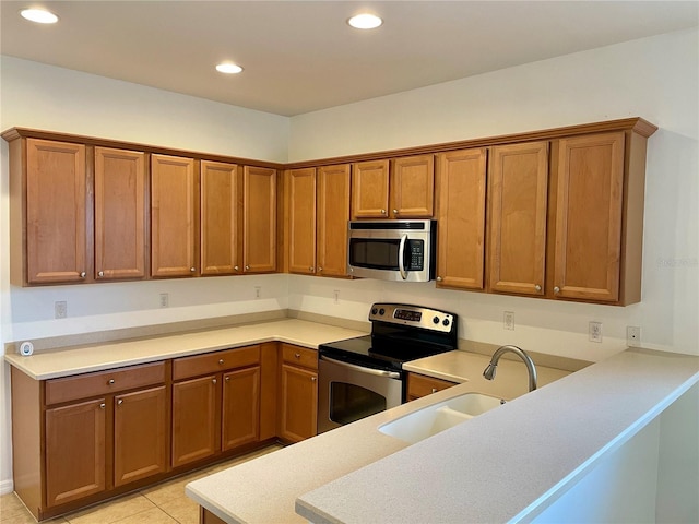 kitchen featuring sink, light tile patterned floors, stainless steel appliances, and kitchen peninsula